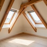 Combles lumineux avec deux fenêtres de toit installées entre les poutres apparentes, protégées par des pare-soleil pour limiter la surchauffe.