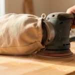 Sac en toile fabriqué pour une ponceuse, recueillant efficacement la poussière de bois dans un atelier.