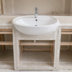 Meuble de salle de bain en plaques de plâtre avec une ossature renforcée supportant une vasque blanche moderne.