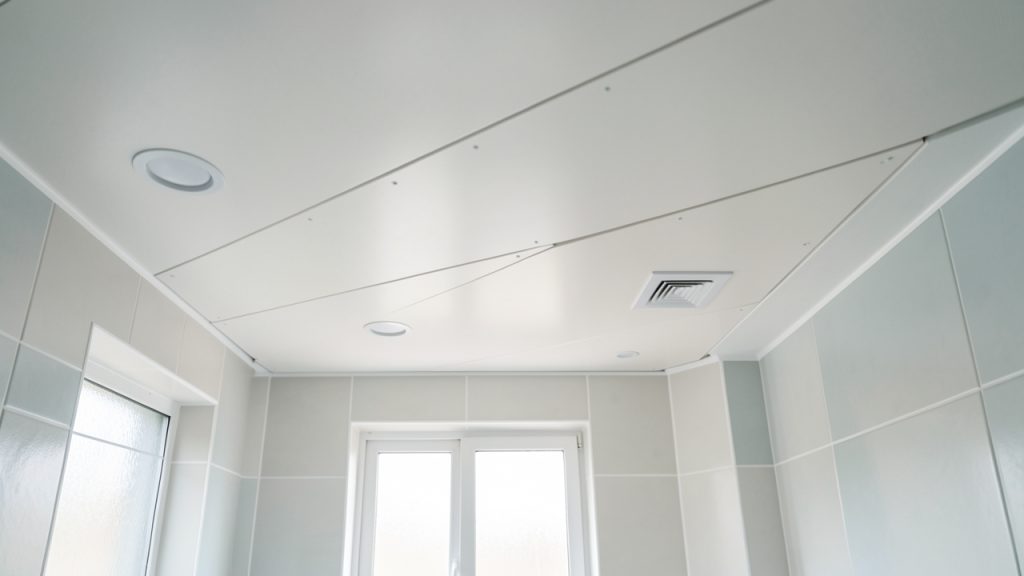 Installation soignée de lambris PVC au plafond d’une salle de bain moderne, avec finitions propres et matériaux résistants à l’humidité.